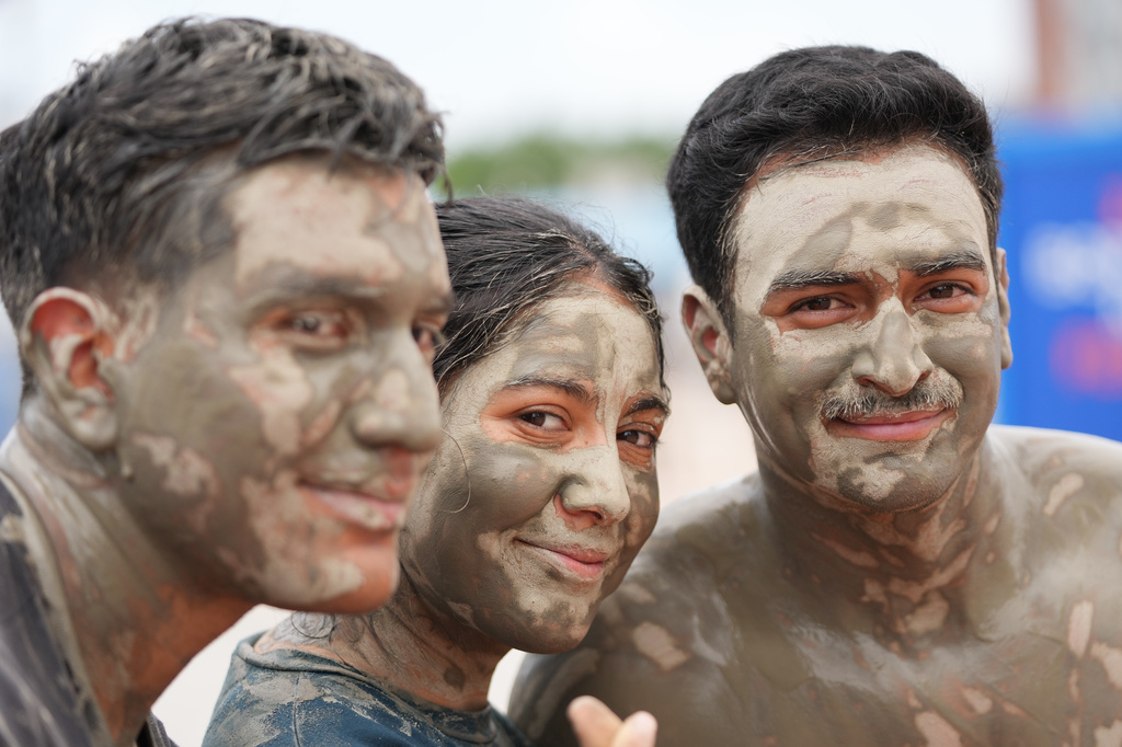 Tourists covered in mud pose for a photo during the Boryeong Mud Festival near a beach in Boryeong, South Korea, Saturday, July 25, 2026. (AP Photo/Lee Jin-man)