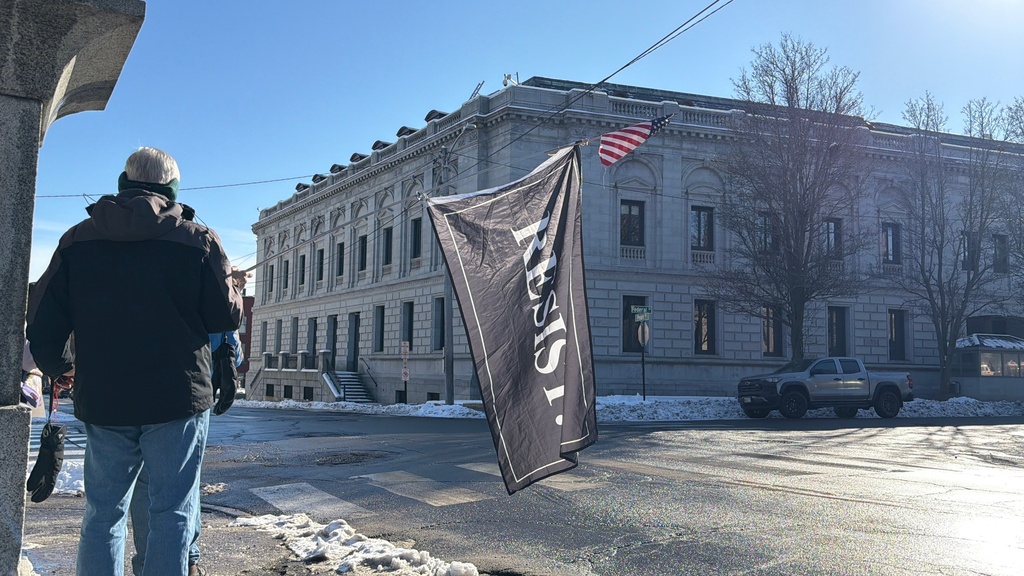 A protester holds a "Resist" flag in front of federal court in Portland, Maine as Immigration and Customs Enforcement conduct operations in the state, Thursday, Jan. 22, 2026. (AP Photo/Rodrique Ngowi)