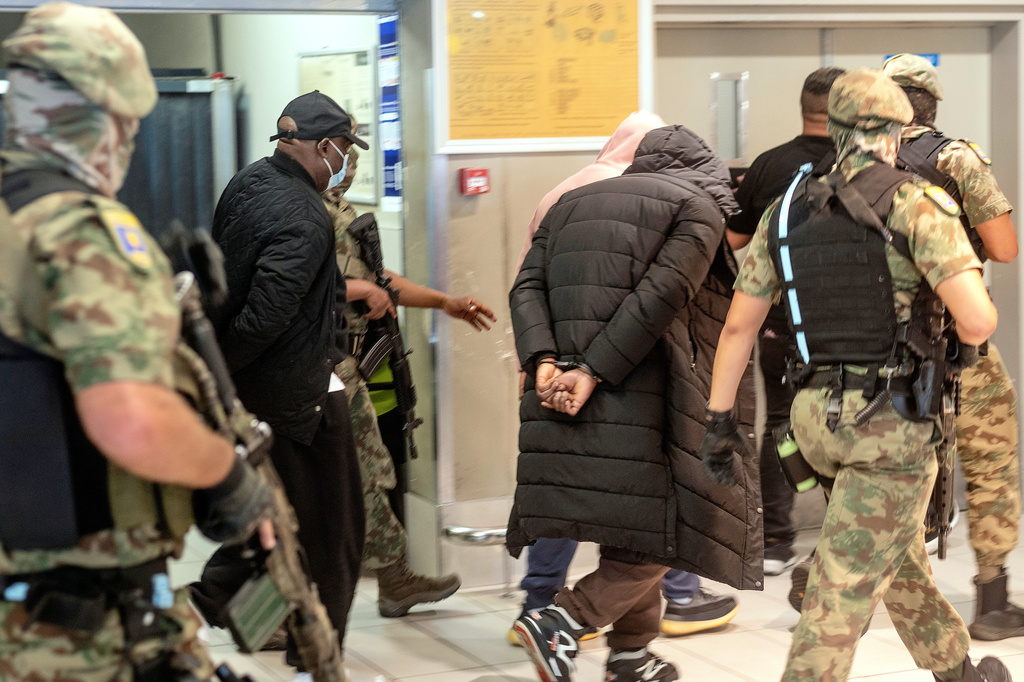 Members of the elite tactical police unit escort six Nigerians nationals being extradited to US for participating in romance scams, in Cape Town, South Africa, Friday, Sept. 11, 2026. (AP Photo)
