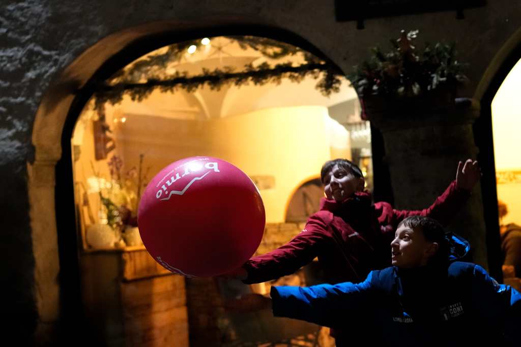 Boys play with a balloon while watching the opening ceremony of the 2026 Winter Olympics at Piazza Cavour, Friday, Feb. 6, 2026, in Bormio, Italy. (AP Photo/Julia Demaree Nikhinson)