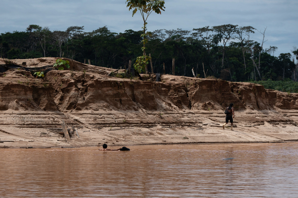 Illegal miners flee as members of the Peruvian Navy arrive near the Malinowski River in the Tambopata National Reserve in Puerto Maldonado, Peru, Tuesday, Aug. 11, 2026. (AP Photo/Guadalupe Pardo)