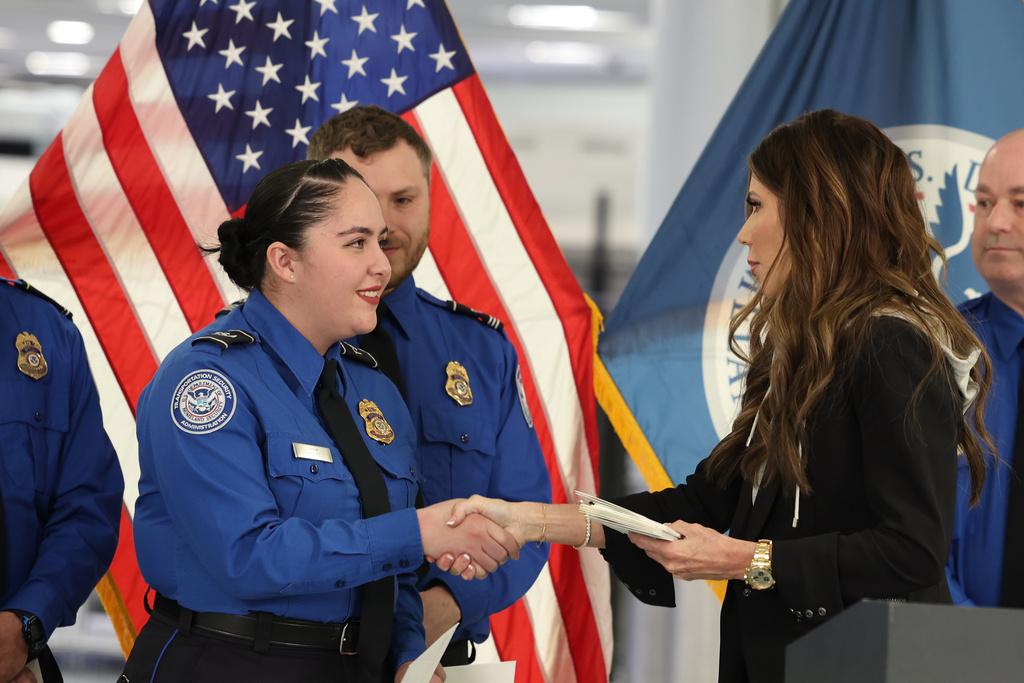U.S. Homeland Security Secretary Kristi Noem, right, shakes hands with Transportation Security Administration Officer Monica Degro at a news conference at Harry Reid International Airport, Saturday, Nov. 22, 2025, in Las Vegas. (AP Photo/Ronda Churchill)
