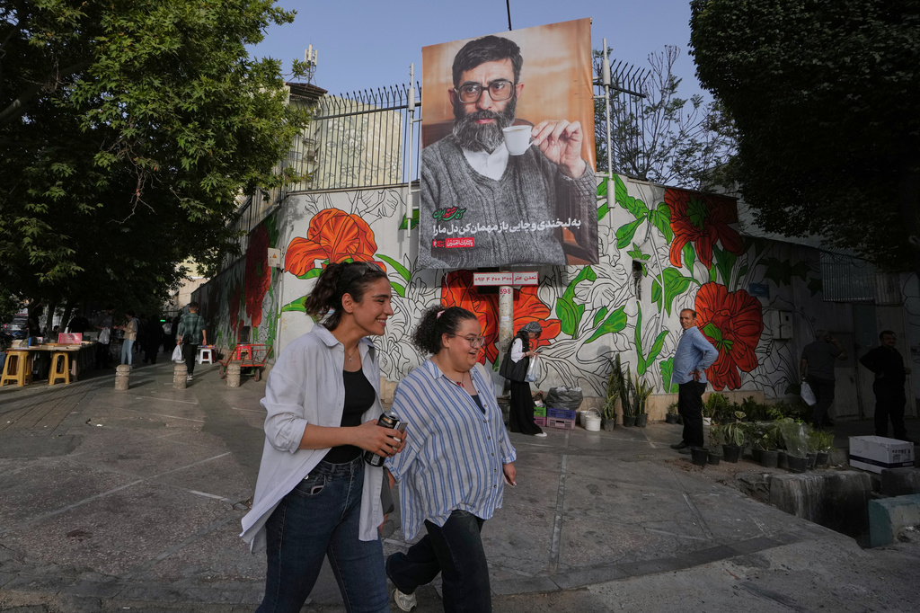 People walk past a banner which shows a portrait of slain Iranian Supreme Leader Ayatollah Ali Khamenei, ahead of his funeral ceremonies in Tehran, Iran, Thursday, July 2, 2026. (AP Photo/Vahid Salemi)