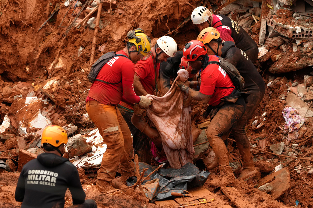 Firefighters recover a body from the site where homes collapsed during heavy rains and severe flooding in the Parque Burnier neighborhood of Juiz de Fora, Minas Gerais state, Brazil, Tuesday, Feb. 24, 2026. (AP Photo/Silvia Izquierdo)