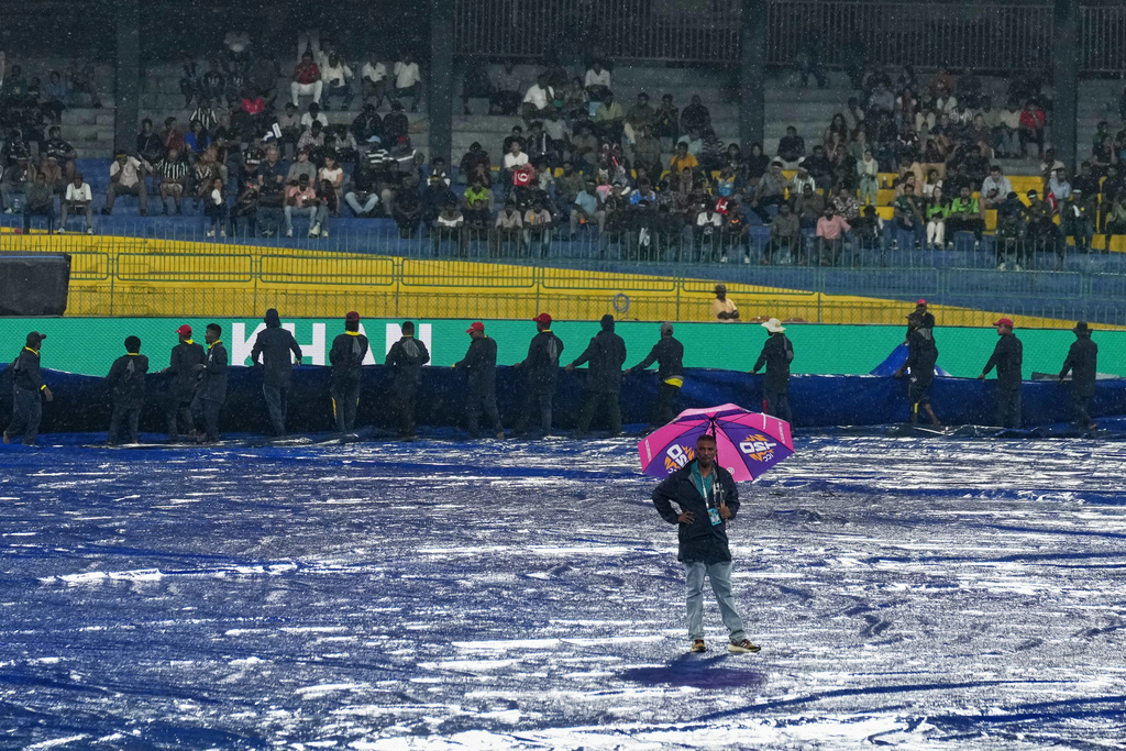 The pitch curator inspects and groundsmen cover the field as it begins to rain before the start of the T20 World Cup cricket match between New Zealand and Pakistan in Colombo, Sri Lanka, Saturday, Feb. 21, 2026. (AP Photo/Eranga Jayawardena)