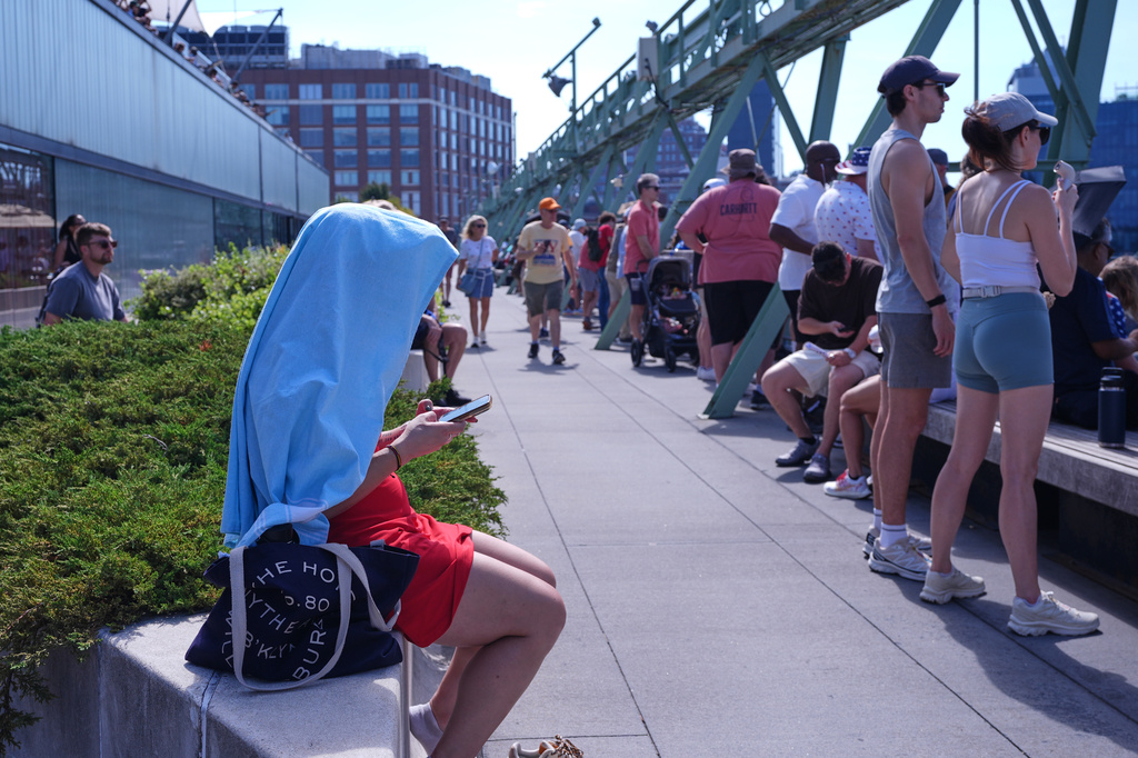 A person shields themselves from the sun at Pier 57 during a heat wave ahead of the International Parade of Sail, Saturday, July 4, 2026, in New York. (AP Photo/Sydney Schaefer)
