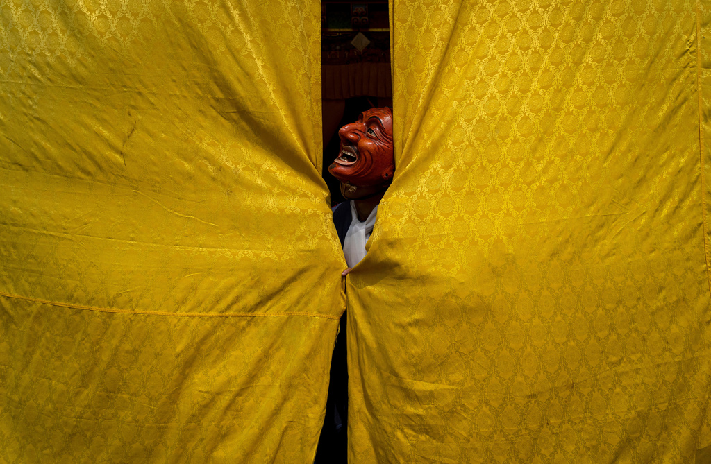 A masked monk stands behind a curtain, assisting a dancer in preparing for a traditional performance, during Gyalpo Losar, the Sherpa community's New Year celebration, at Shechen Monastery, in Kathmandu, Nepal, Feb. 25, 2025. (AP Photo/Niranjan Shrestha, File)