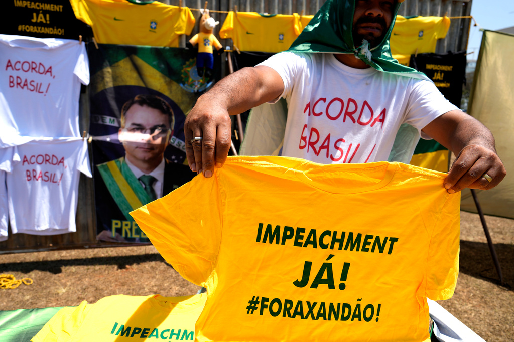 A vendor holds up a T-shirt that reads in Portuguese: "Impeachment now! Out with Xandao," a nickname for Supreme Court Justice Alexandre de Moraes, during a protest by supporters of presidential candidate Sen. Flavio Bolsonaro calling for Moraes' impwldeachment in Brasilia, Brazil, Tuesday, Sept. 15, 2026. (AP Photo/Eraldo Peres)