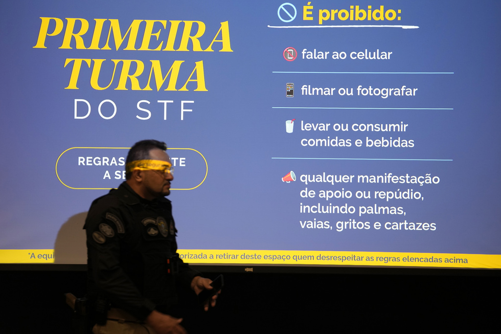 A security guard walks in front of a panel listing the rules for attendees of the verdict and sentencing phase of a trial for those charged in an alleged coup plot to keep former President Jair Bolsonaro in office after his 2022 election defeat, in Brasilia, Brazil, Tuesday, Sept. 9, 2025. (AP Photo/Eraldo Peres)