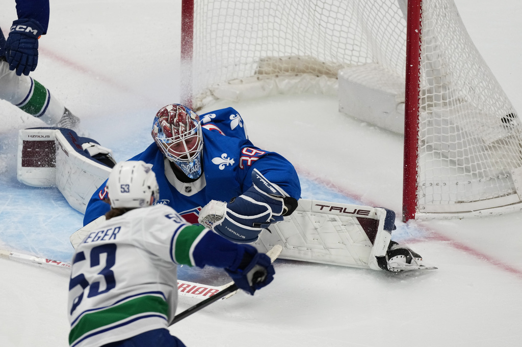 Vancouver Canucks center Teddy Blueger, front, scores a goal past Colorado Avalanche goaltender MacKenzie Blackwood in the first period of an NHL hockey game, Wednesday, April 1, 2026, in Denver. (AP Photo/David Zalubowski)