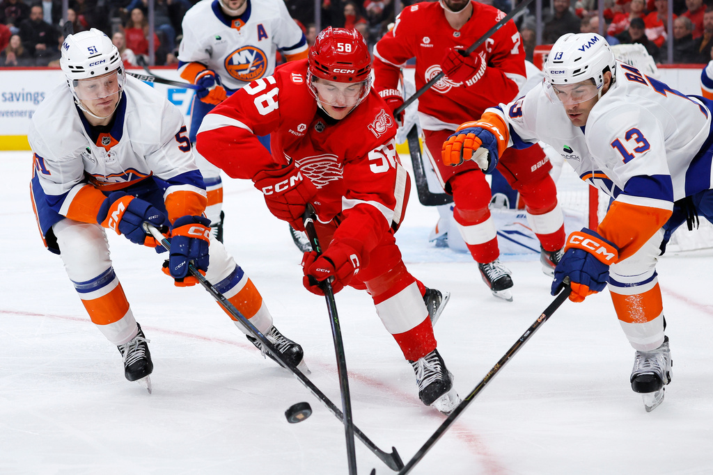 Detroit Red Wings center Emmitt Finnie (58) battles New York Islanders left wing Emil Heineman (51) and center Mathew Barzal (13) for the puck during the second period of an NHL hockey game Tuesday, Dec. 16, 2025, in Detroit. (AP Photo/Duane Burleson)