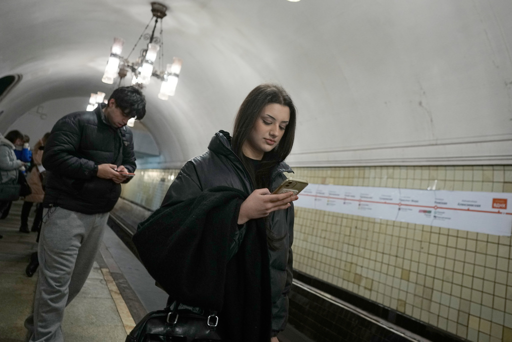 A young woman looks at her smartphone while on the subway in Moscow, Wednesday, Feb. 11, 2026. (AP Photo/Alexander Zemlianichenko)