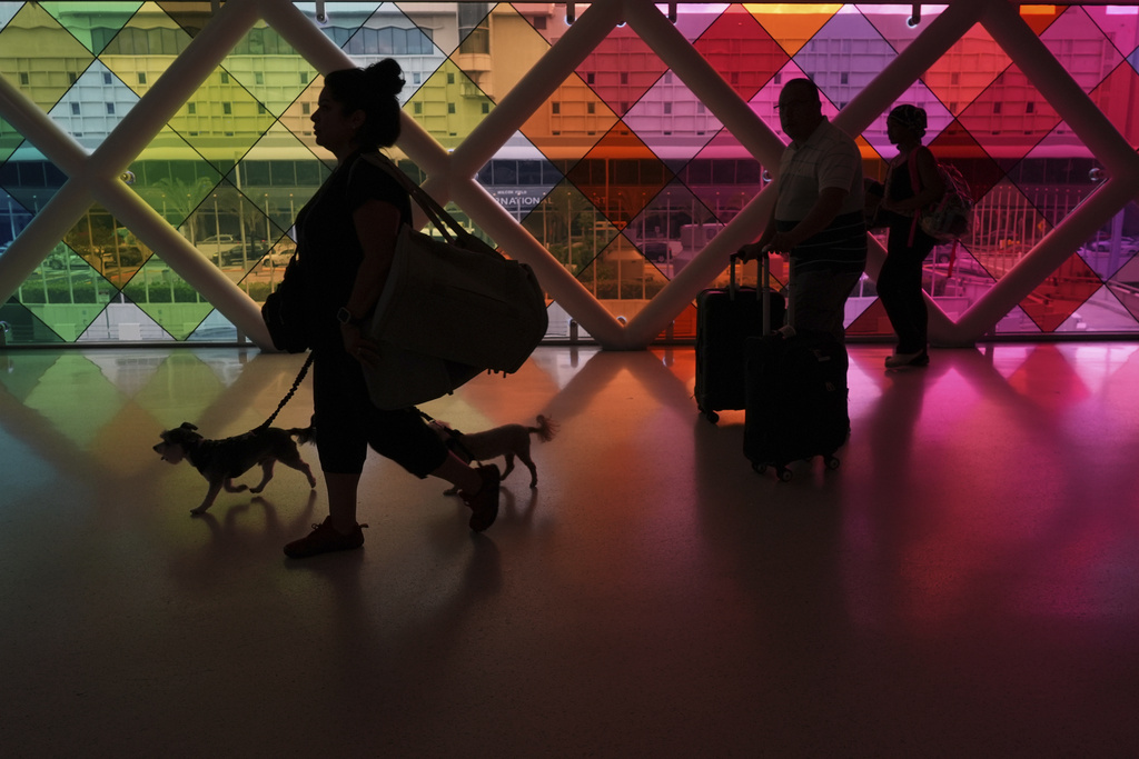 Travelers walk toward an exit at Miami International Airport at the start of the Labor Day weekend, Friday, Aug. 29, 2025, in Miami. (AP Photo/Rebecca Blackwell)
