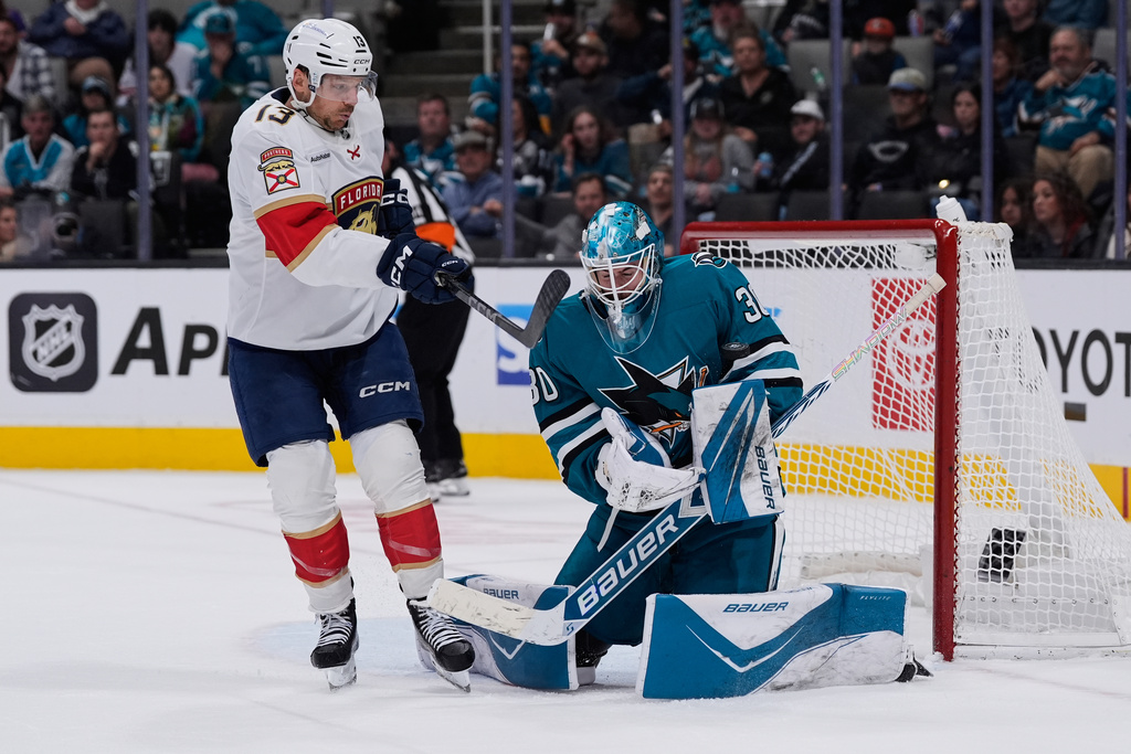 San Jose Sharks goaltender Yaroslav Askarov (30) deflects the puck next to Florida Panthers center Sam Reinhart (13) during the second period of an NHL hockey game, Saturday, Nov. 8, 2025, in San Jose, Calif. (AP Photo/Godofredo A. Vásquez)