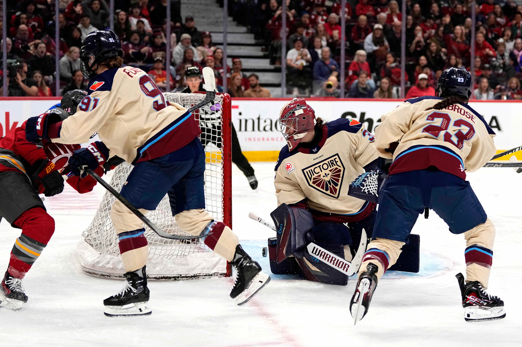 The puck rolls through the crease of Montreal Victoire goaltender Sandra Abstreiter, second from right, off a shot by Ottawa Charge's Gabbie Hughes, left, during third-period PWHL hockey game action in Ottawa, Ontario, Friday, April 3, 2026. (Justin Tang/The Canadian Press via AP)