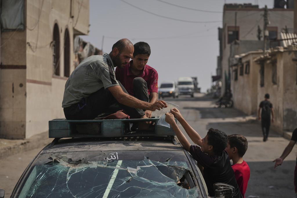 Palestinian children buy bags of drinking water during a heat wave in Deir al-Balah, central Gaza Strip, Wednesday, Aug, 13, 2025. (AP Photo/Abdel Kareem Hana)
