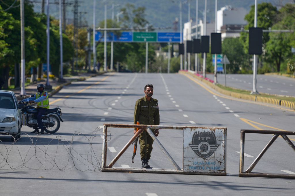 A police officer stands guard at a checkpoint on a barricaded road to ensure security ahead of the second round of the U.S. Iran officials talks, in Islamabad, Pakistan, Sunday, April 19, 2026. (AP Photo/M.A. Sheikh)