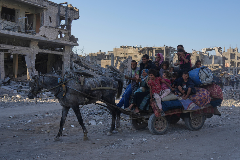 Displaced Palestinians ride on a horse-drawn cart loaded with belongings as they pass along the heavily damaged Al-Jalaa Street in Gaza City, Saturday, Oct. 11, 2025, after Israel and Hamas agreed to a pause in their war and the release of the remaining hostages. (AP Photo/Abdel Kareem Hana)