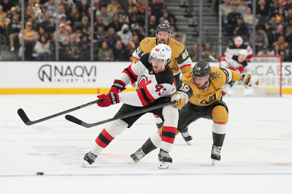 New Jersey Devils defenseman Luke Hughes (43) and Vegas Golden Knights right wing Reilly Smith (19) vie for the puck during the first period of an NHL hockey game Wednesday, Dec. 17, 2025, in Las Vegas. (AP Photo/Candice Ward)