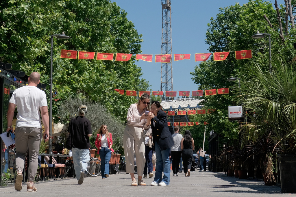 Pedestrians walk on a street decorated with national flags in Montenegro's capital Podgorica, Monday, May 18, 2026. (AP Photo/Risto Bozovic)