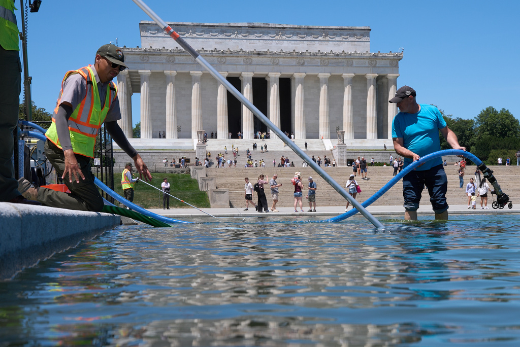 Members of the National Park Service and contractors place a tube into the Lincoln Memorial Reflecting Pool, as the pool is cleaned of algae, Tuesday, June 16, 2026, in Washington. (AP Photo/Jacquelyn Martin)