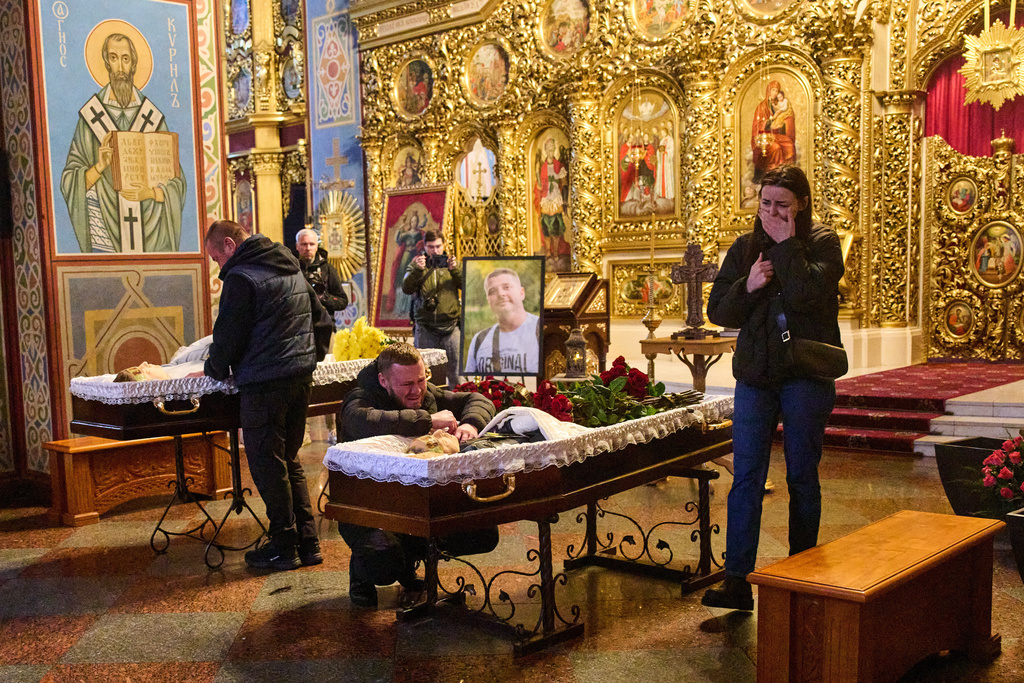 Relatives, colleagues and friends of two Ukrainian 43-year-old journalists Olena Hubanova, who worked under the pseudonym Alyona Gramova, and cameraman Yevhen Karmazin, who were killed on Thursday, Oct. 23, when a Russian Lancet drone hit their vehicle in Ukraine's Kramatorsk around 20 kilometres from the front line, mourn over their coffins during a funeral service at St. Michael Monastery in Kyiv, Ukraine, Monday, Oct. 27, 2025. (AP Photo/Efrem Lukatsky)
