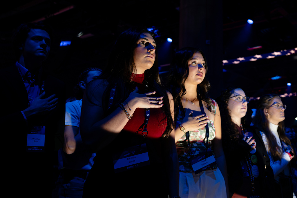 Attendees observe the National Anthem during Turning Point USA's AmericaFest 2025, Saturday, Dec. 20, 2025, in Phoenix. (AP Photo/Jon Cherry)