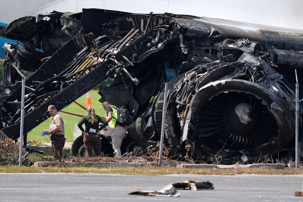 Officials stand near a destroyed wing and engine as they inspect an Amazon cargo plane two days after it overshot a runway at Miami International Airport, Tuesday, Sept. 8, 2026, in Miami. (AP Photo/Rebecca Blackwell)