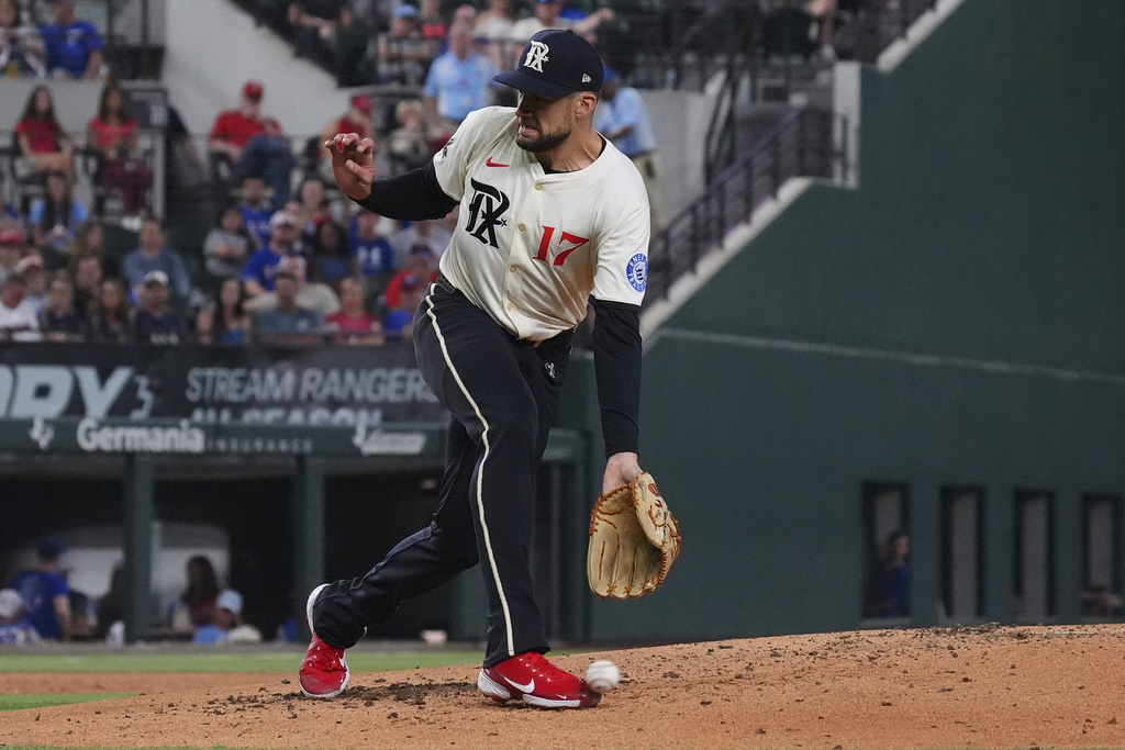 Texas Rangers starting pitcher Nathan Eovaldi reaches for a groundout hit by Cleveland Guardians' Steven Kwan during the third inning of a baseball game, Friday, Aug. 22, 2025, in Arlington, Texas. (AP Photo/LM Otero)