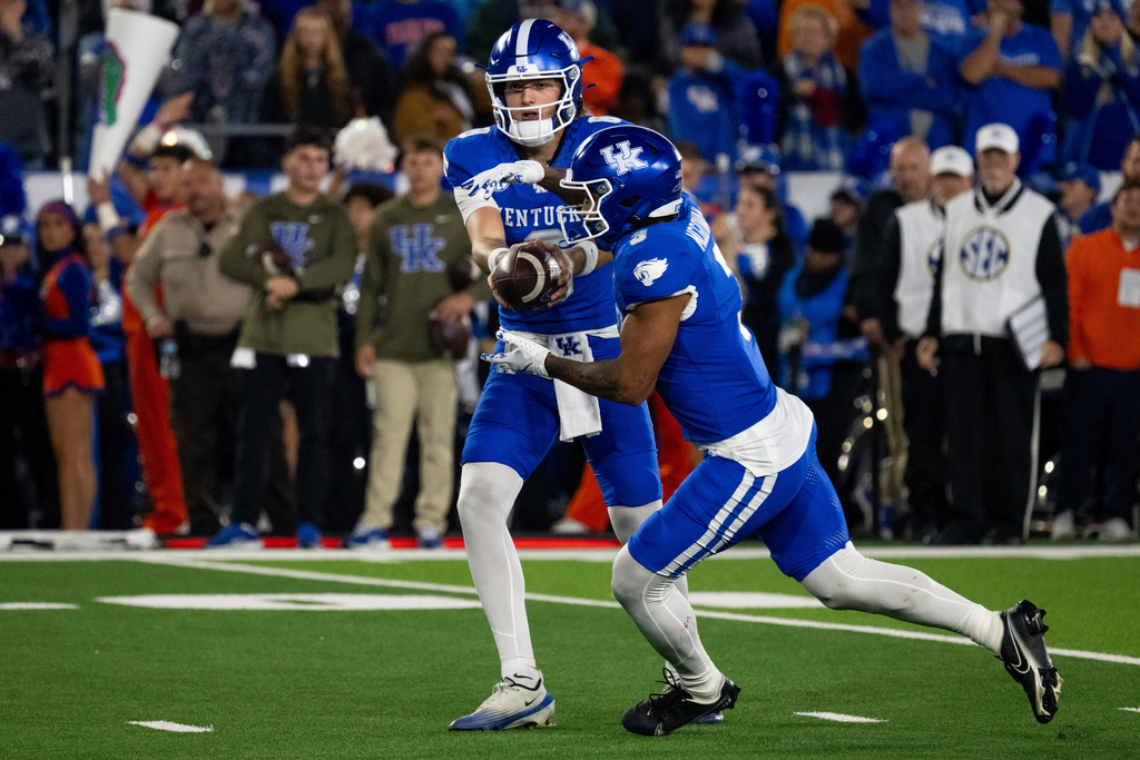 Kentucky quarterback Cutter Boley (8) hand the ball off to running back Seth McGowan (3) in the second quarter of an NCAA college football game against Florida, Saturday, Nov. 8, 2025, in Lexington, Ky. (AP Photo/Michael Swensen)