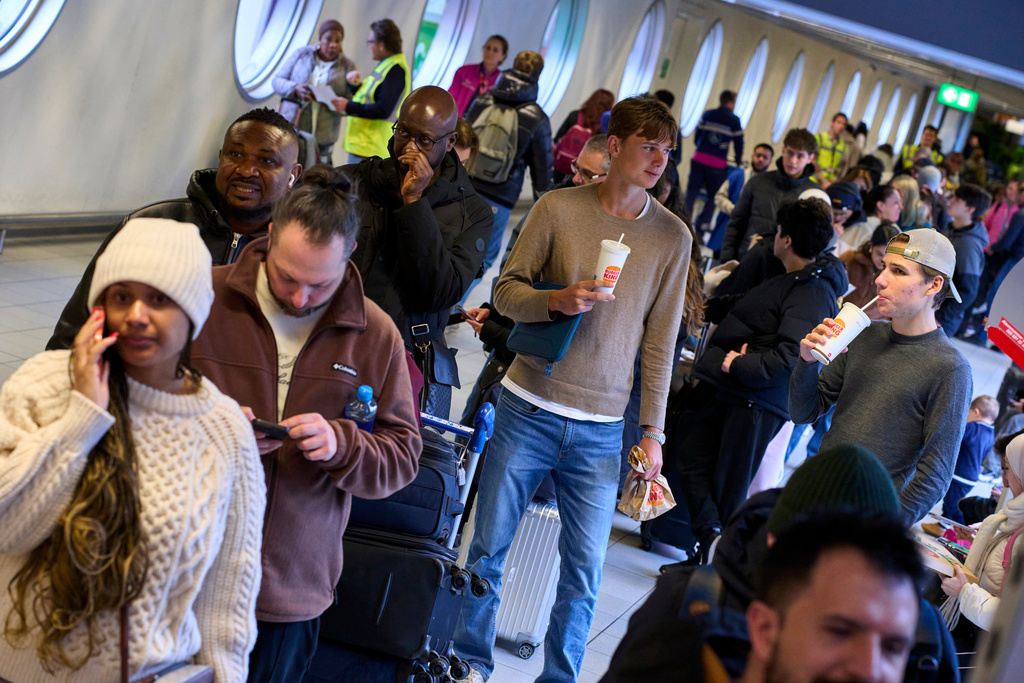 Stranded travellers queue at the information desk at Schiphol airport in Amsterdam, Netherlands, Wednesday, Jan. 7, 2026, where more than 1,000 people spent the night as snow and ice that is pummeling parts of Europe grounded hundreds of flights and choked highways and railroads. (AP Photo/Peter Dejong)