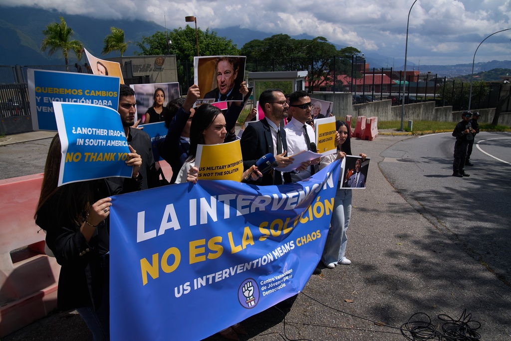 Gabriel Cabrera, president of the Venezuelan Youth Center for Democracy, gives a statement outside of the U.S. embassy with members of the organization holding signs that read in Spanish "Intervention is not the solution," in reference to U.S. warships operating in the Caribbean, in Caracas, Venezuela, Monday, Oct. 27, 2025. (AP Photo/Ariana Cubillos)