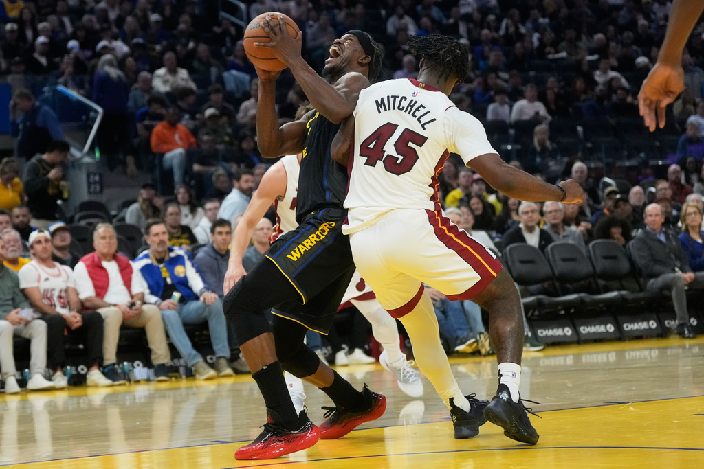 Golden State Warriors forward Jimmy Butler III, left, reacts after contact with Miami Heat guard Davion Mitchell (45) during the second half of an NBA basketball game in San Francisco, Monday, Jan. 19, 2026. (AP Photo/Jeff Chiu)