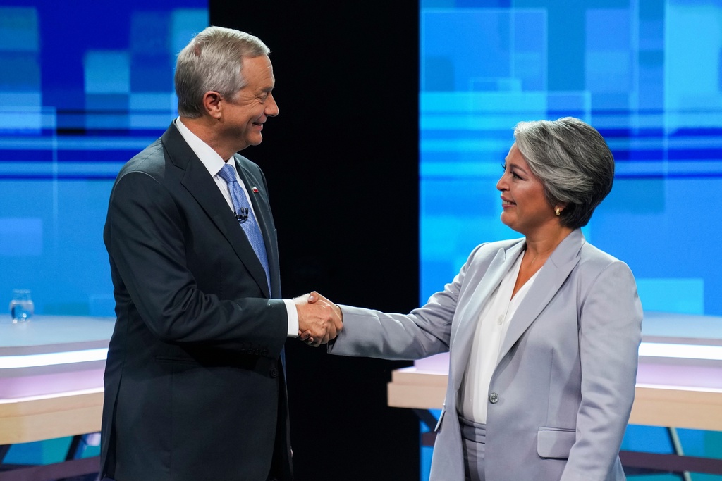 Presidential candidates Jose Antonio Kast of the Republican Party and Jeannette Jara of the Unity for Chile coalition shake hands during a debate ahead of runoff elections in Santiago, Chile, Tuesday, Dec. 9, 2025. (AP Photo/Esteban Felix)