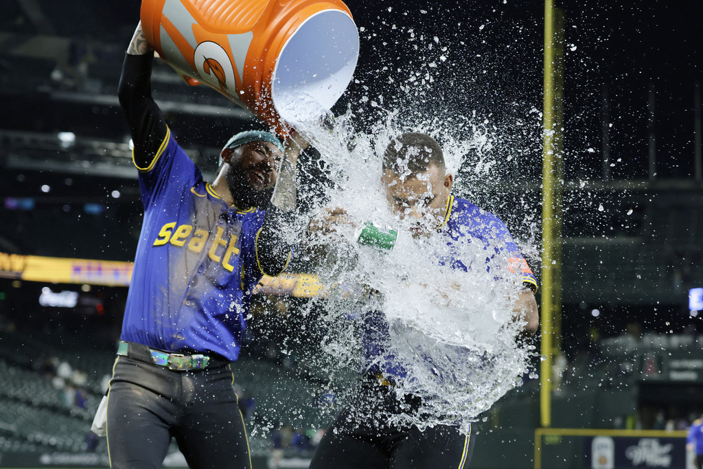 Seattle Mariners' Harry Ford is doused with ice water by J.P. Crawford after his walkoff sacrifice fly against the Los Angeles Angels during the 12th inning of a baseball game Thursday, Sept. 11, 2025, in Seattle. (AP Photo/John Froschauer)