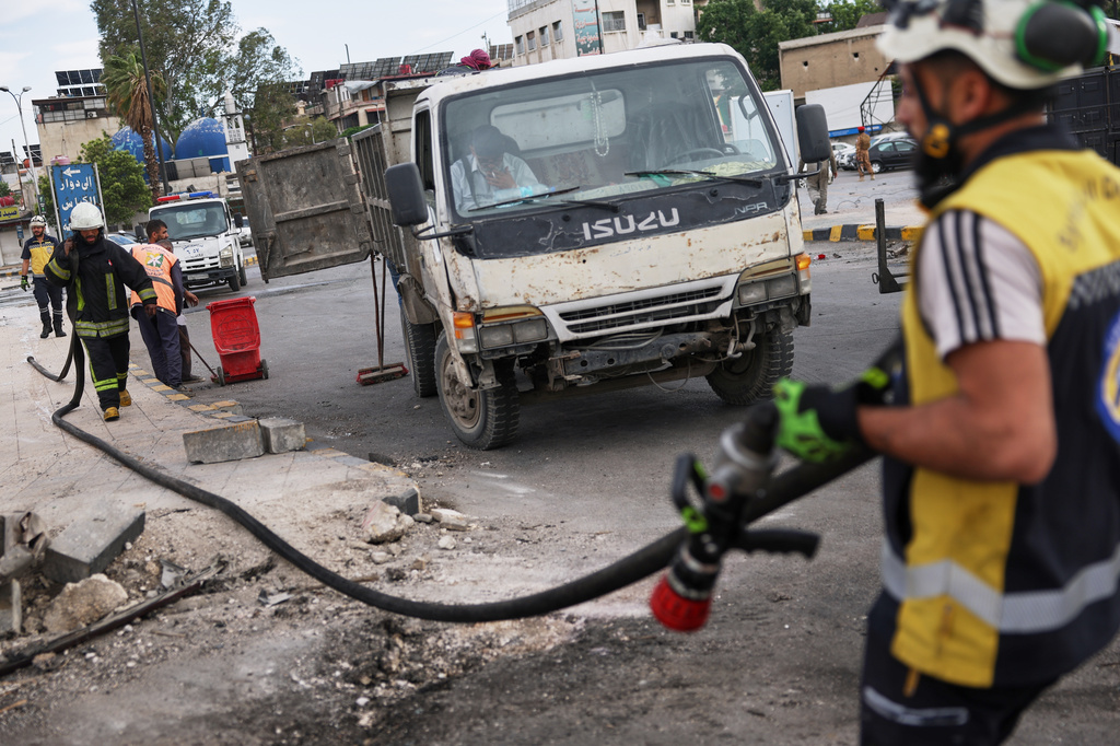 Workers clean the area at the site of an explosion outside a Defense Ministry building in Damascus, Syria, Tuesday, May 19, 2026. (AP Photo/Ghaith Alsayed)