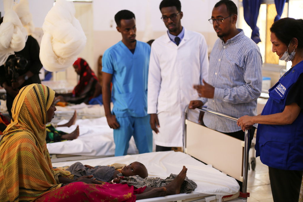 Health workers talk to a woman with her malnourished baby at Bay Hospital in Baidoa, Somalia, Tuesday, Aug. 4, 2026. (AP Photo/Mohamed Sheikh Nor)