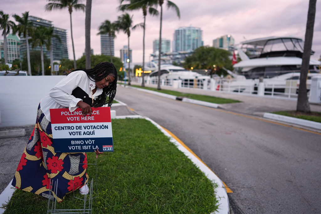 Polling place supervisor Bridget Knighton installs a sign directing voters to a voting site at Miami City Hall, on Election Day, Tuesday, Nov. 4, 2025, in Miami. (AP Photo/Rebecca Blackwell)