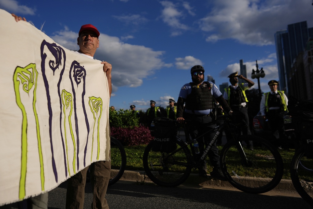 Police watch as people hold up signs as they gather during Illinois Coalition for Immigrant & Refugee Rights' "Chicago Says No Trump No Troops" protest Saturday, Sept. 6, 2025, in Chicago. (AP Photo/Carolyn Kaster)