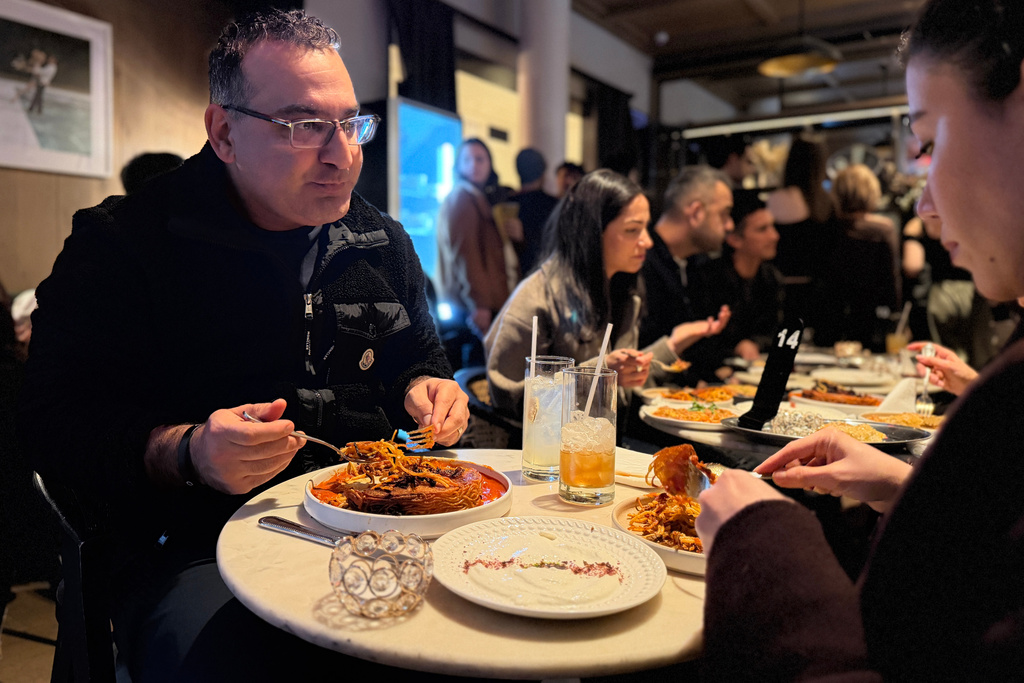 Kayvon Pourmirzaie and his wife, Behnaz Almazi, eat a tahdig-like pasta dish, based on a classic Iranian crispy rice dish, during a Persian pop-up dinner to celebrate Nowruz in New York on Saturday, March 14, 2026. (AP Photo/J.M. Hirsch)