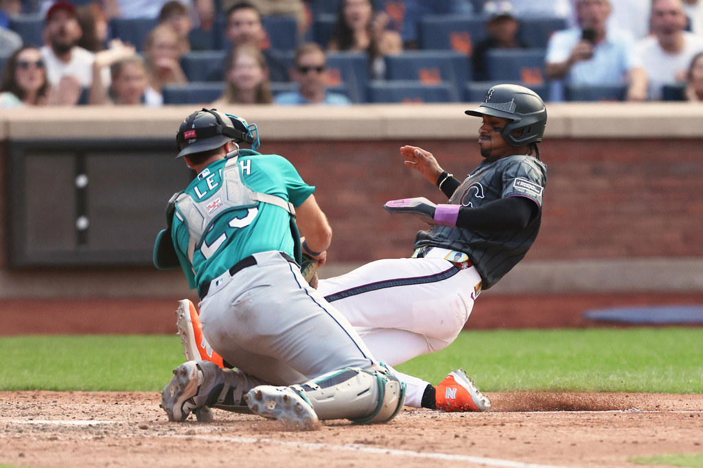 New York Mets' Francisco Lindor, right, is tagged out at home plate by Seattle Mariners catcher Cal Raleigh, left, during the seventh inning of a baseball game, Saturday, Aug. 16, 2025, in New York. (AP Photo/Heather Khalifa)