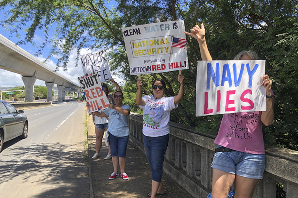 FILE - Protestors upset with the Department of Defense's response to the leak of jet fuel into the water supply hold signs outside the gate at Joint Base Pearl Harbor-Hickam, Hawaii, Friday, Sept. 30, 2022. (AP Photo/Audrey McAvoy, File)