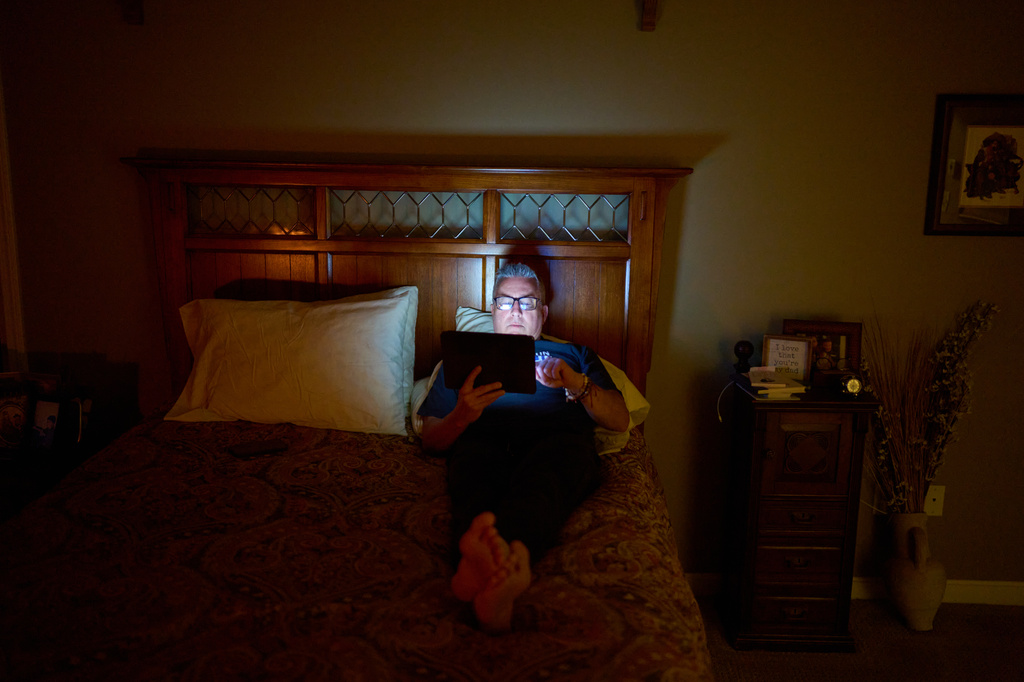 Chris Colocousis, who is still so shaken by a scam that took his retirement savings that he sometimes has trouble leaving his house, looks at a tablet in his bedroom in Raynham, Mass., Tuesday, March 10, 2026. (AP Photo/David Goldman)