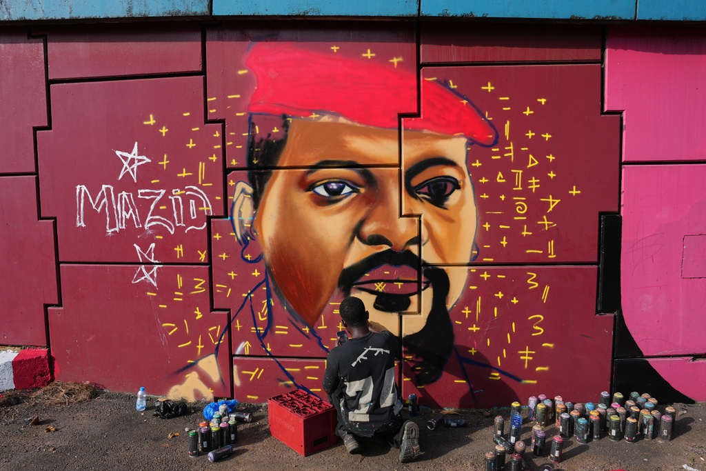 Graffiti artist Omar Diaw works on a mural depicting Guinea's President Mamadi Doumbouya on a street wall in Conakry, Guinea, Saturday, Sep. 20, 2025. (AP Photo/Misper Apawu)