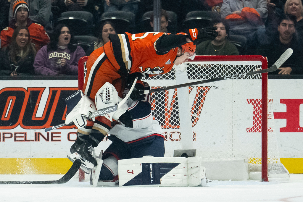 Anaheim Ducks right wing Beckett Sennecke, top, skates into Columbus Blue Jackets goaltender Elvis Merzlikins during the second period of an NHL hockey game, Saturday, Dec. 20, 2025, in Anaheim, Calif. (AP Photo/Kyusung Gong)