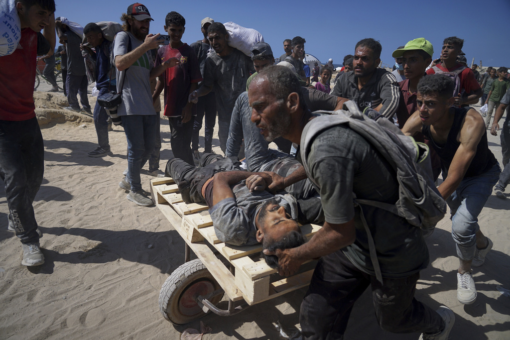 Palestinians are carried after they were wounded while trying to reach trucks carrying humanitarian aid on the outskirts of Beit Lahiya, northern Gaza Strip, Aug. 1, 2025. (AP Photo/Jehad Alshrafi)