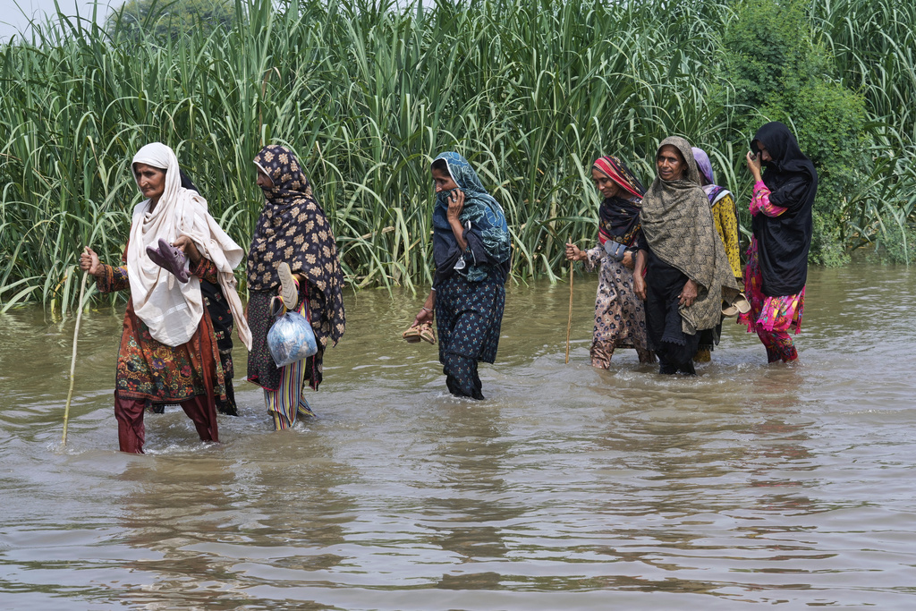 Women wade through a flooded field in Muza Islam Wala, in Jhang district, Pakistan, Tuesday, Sept. 2, 2025. (AP Photo/K.M. Chaudary)
