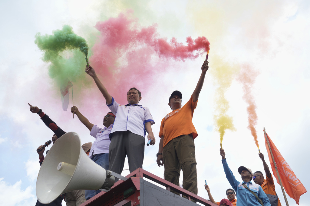 Indonesian laborers light flares during a rally against outsourcing and low wages outside the parliament in Jakarta, Indonesia, Thursday, Aug. 28, 2025. (AP Photo/Tatan Syuflana)
