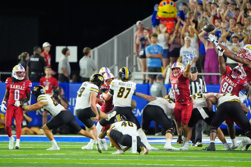 A field goal attempt by Missouri place kicker Blake Craig (19) is blocked before Kansas cornerback Austin Alexander recovered the ball and ran for a touchdown during the first half of an NCAA college football game Friday, Sept. 11, 2026, in Lawrence, Kan. (AP Photo/Charlie Riedel)