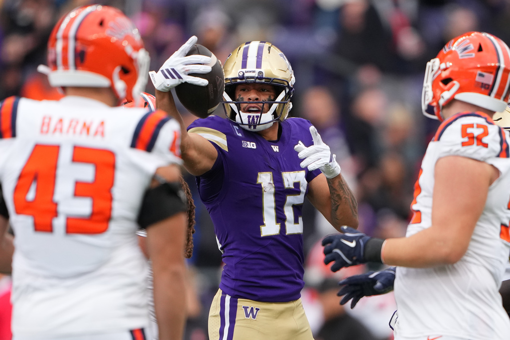Washington wide receiver Denzel Boston (12) reacts after a reception as Illinois defensive end Joe Barna (43) and defensive lineman Pat Farrell (52) look on during the first half of NCAA college football game, Saturday, Oct. 25, 2025, in Seattle. (AP Photo/Lindsey Wasson)